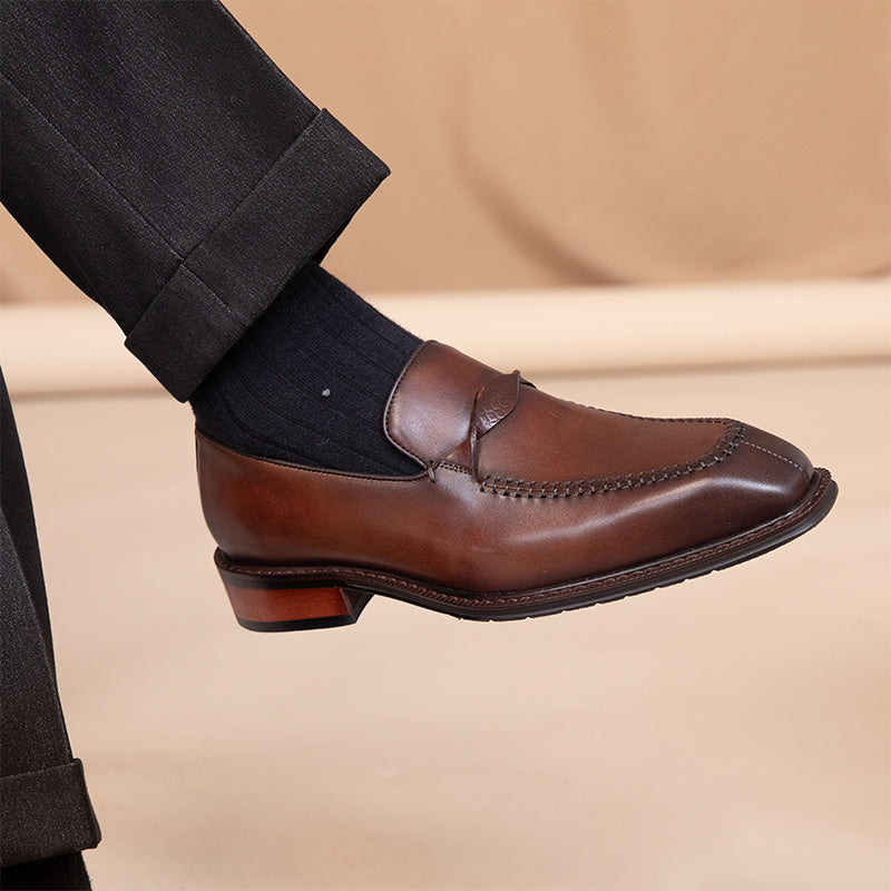 Brown leather loafer on a beige background