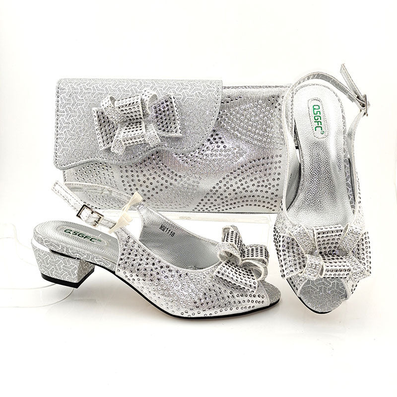Silver shoes and matching handbag with decorative elements on a white background