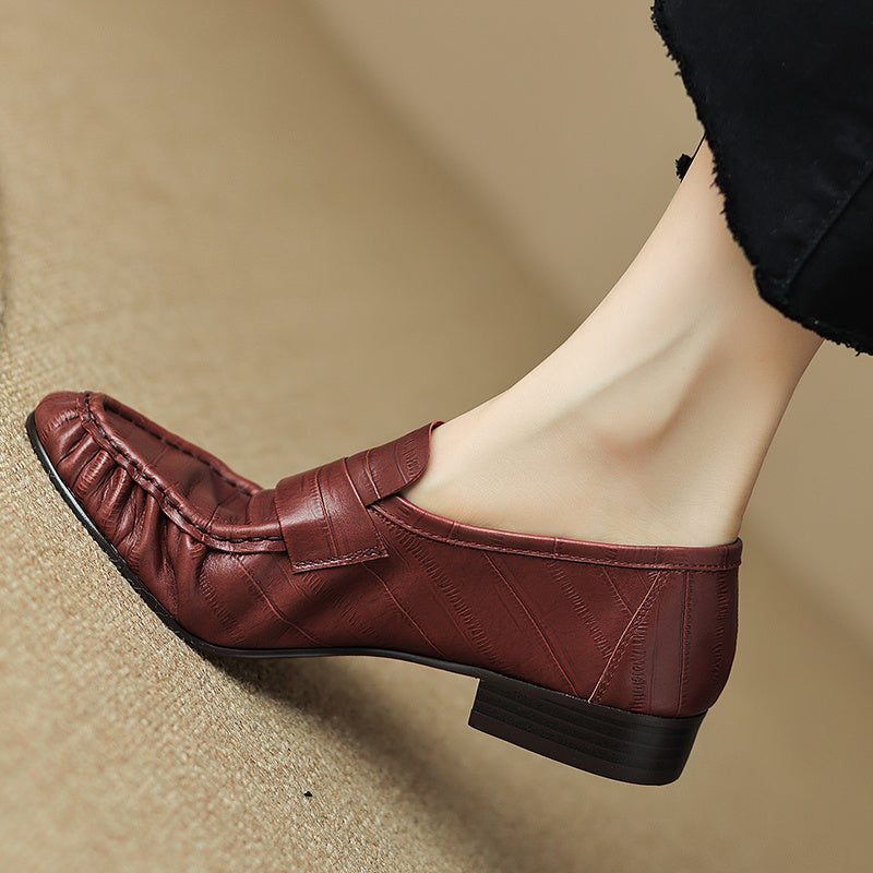 Brown leather loafer shoe on a beige surface