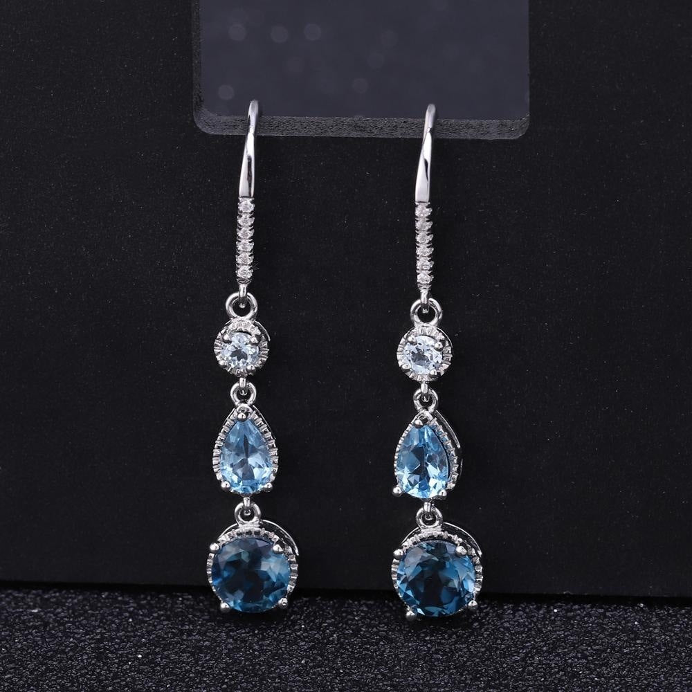 Silver earrings with blue gemstones on a black background
