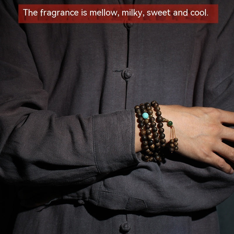 Person wearing a dark shirt with a bracelet on a dark background