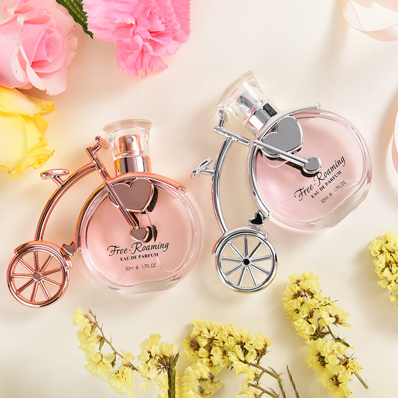 Two pink perfume bottles with floral decorations on a light background