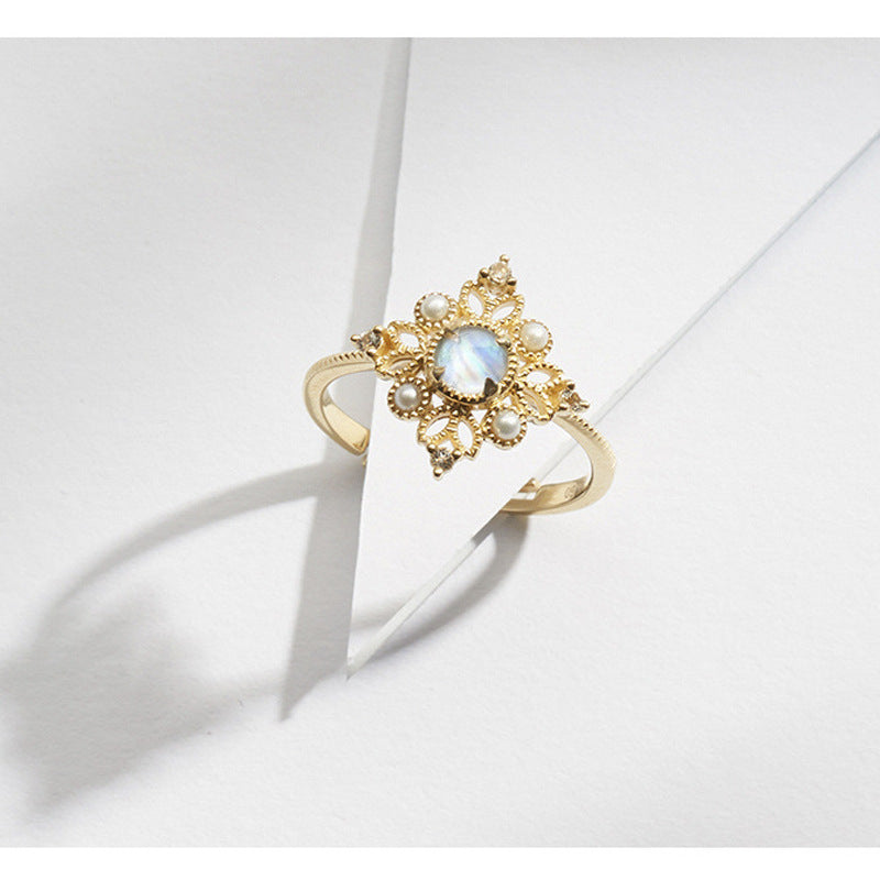 Gold ring with a central gemstone and pearl accents on a light background