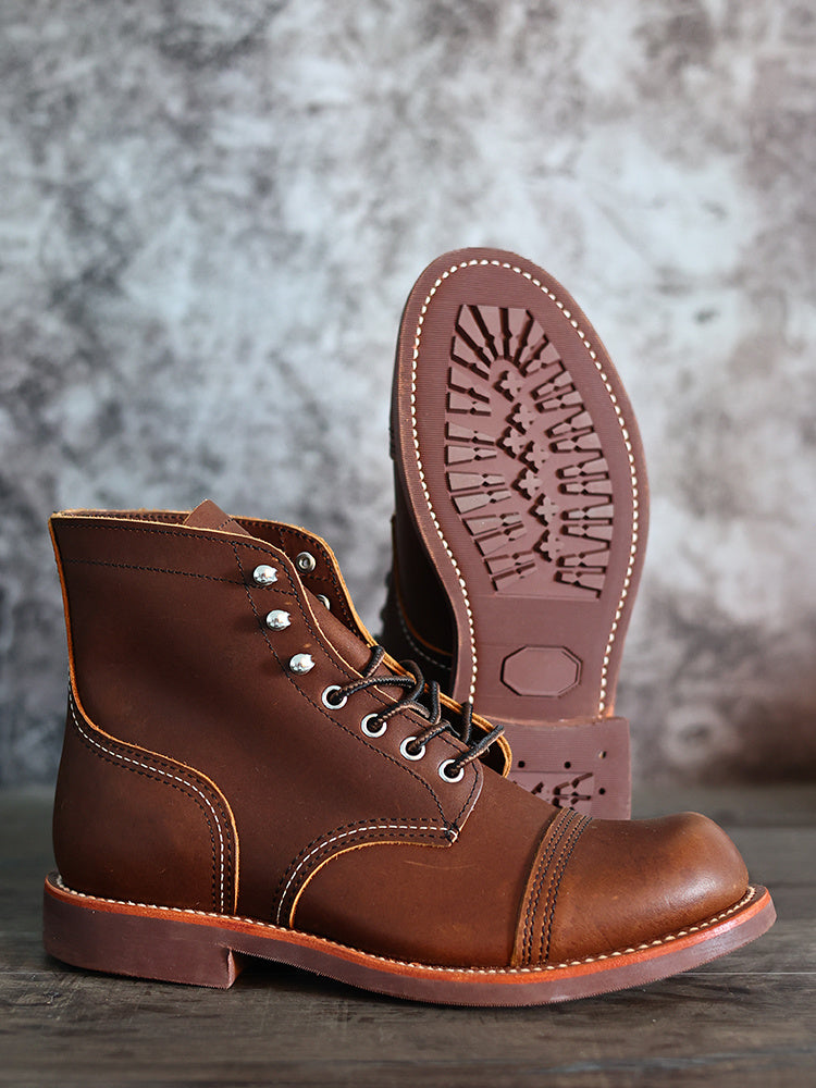 Brown leather boot with detailed sole on a textured surface