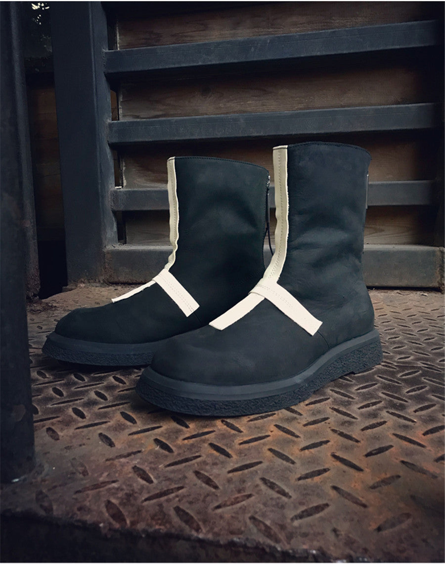 Black boots with white accents on a textured metal surface