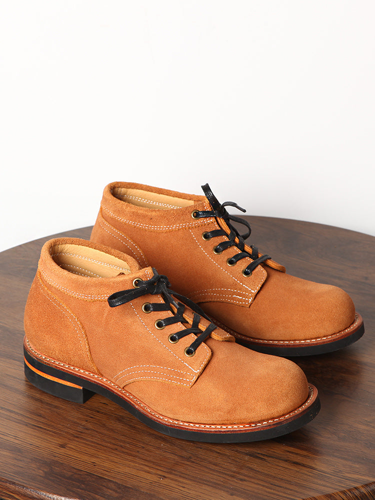 Pair of brown leather shoes with black laces on a wooden surface