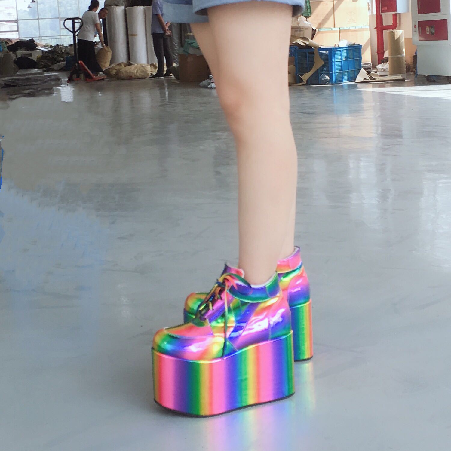 Multicolored platform shoes on a reflective floor with people in the background.