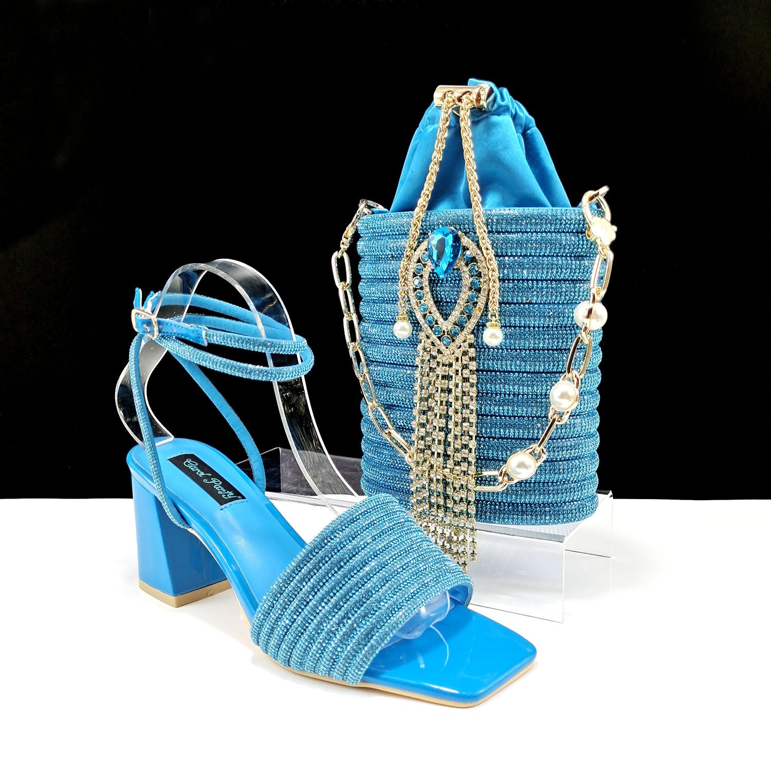 Blue beaded sandal and matching bag on a clear stand with a black background