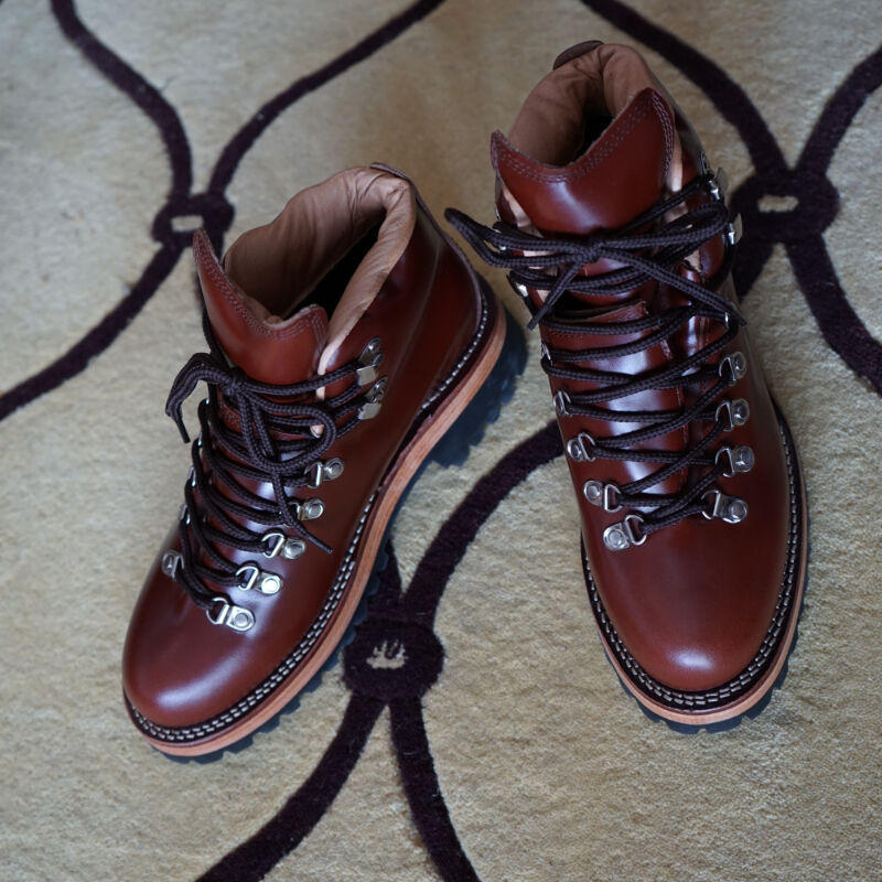 Pair of brown leather boots with black laces on a textured surface