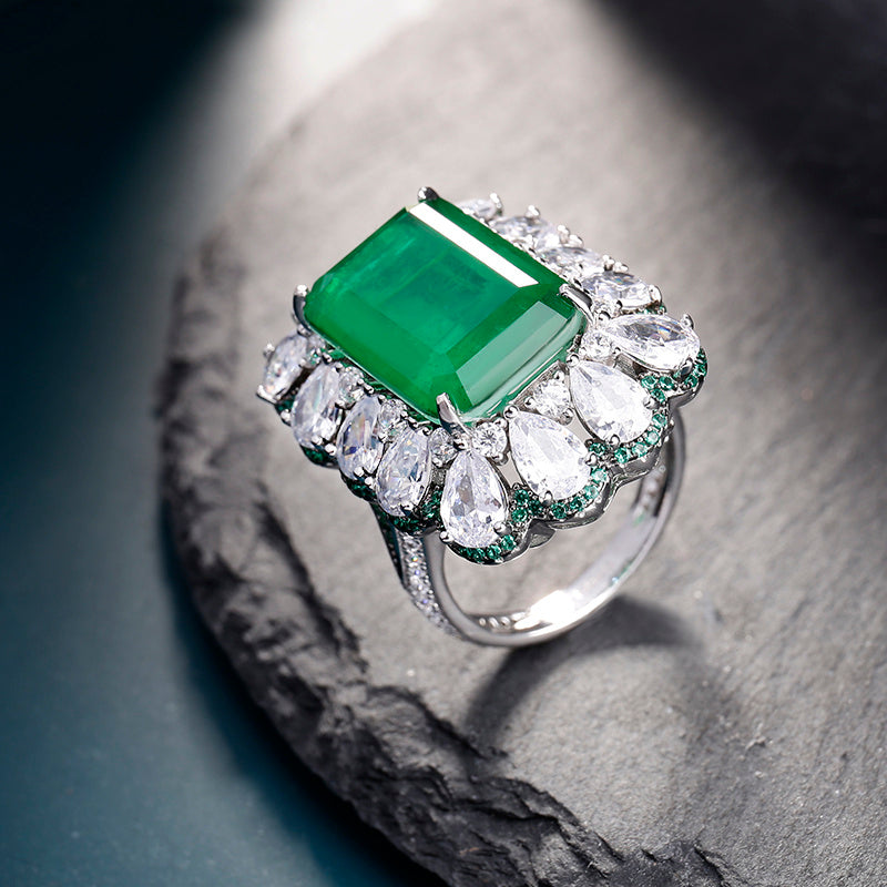 Ring with a green gemstone and diamond-like stones on a stone surface