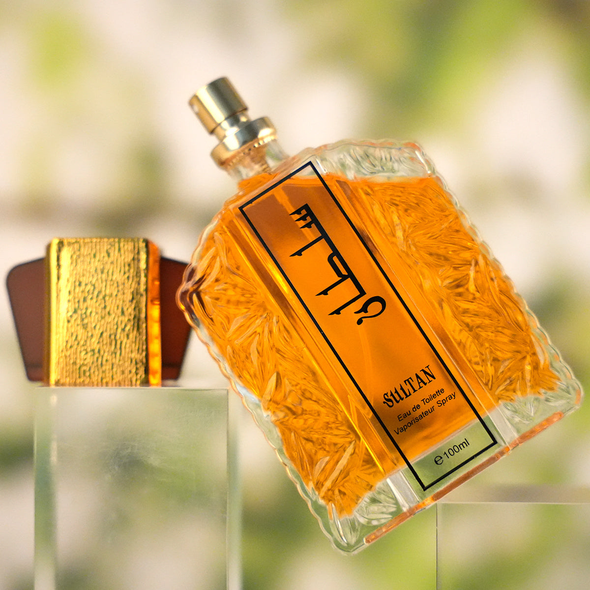 Perfume bottle with gold cap and decorative label on a blurred natural background