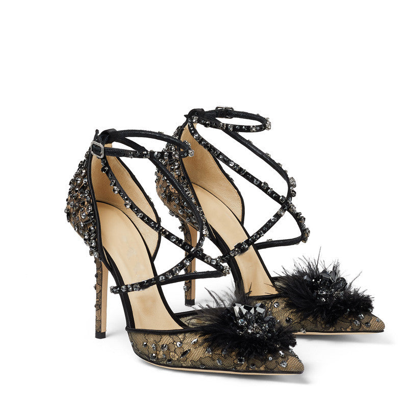 Black high-heeled shoes with embellishments and feathers on a white background