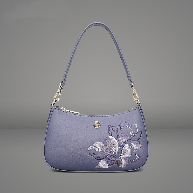Purple handbag with floral embroidery on a gray background