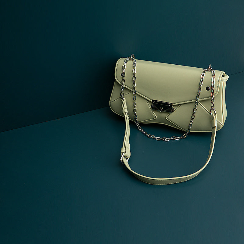 Green handbag with a chain detail on a dark blue background