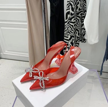 Red high-heeled shoes with crystal embellishments on a white platform.