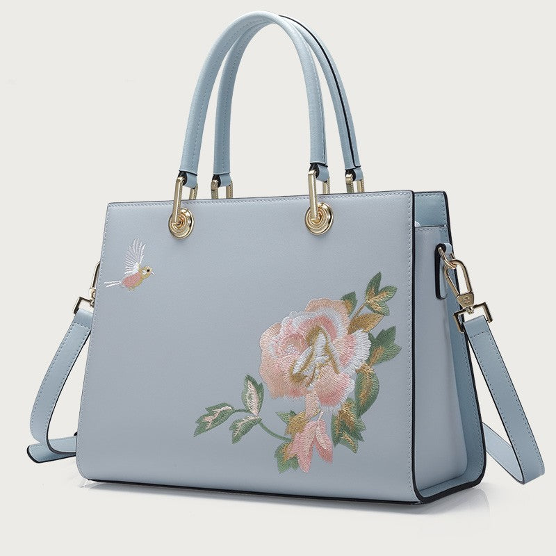 Light blue handbag with floral embroidery on a light gray background