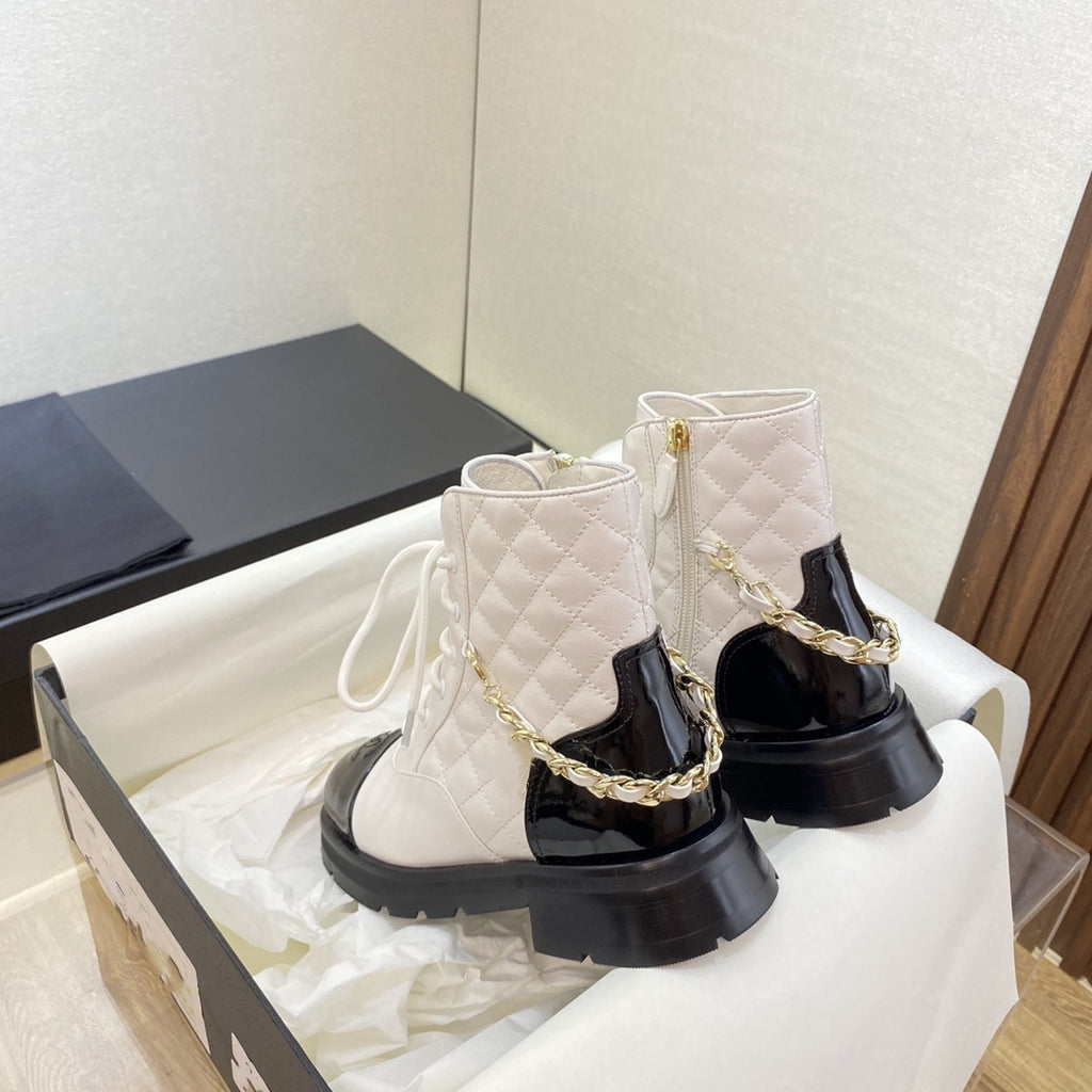 White quilted ankle boots with gold chain detail on a white surface.