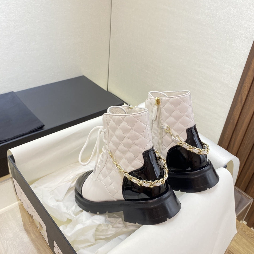 White quilted ankle boots with gold chain detail on a white surface.