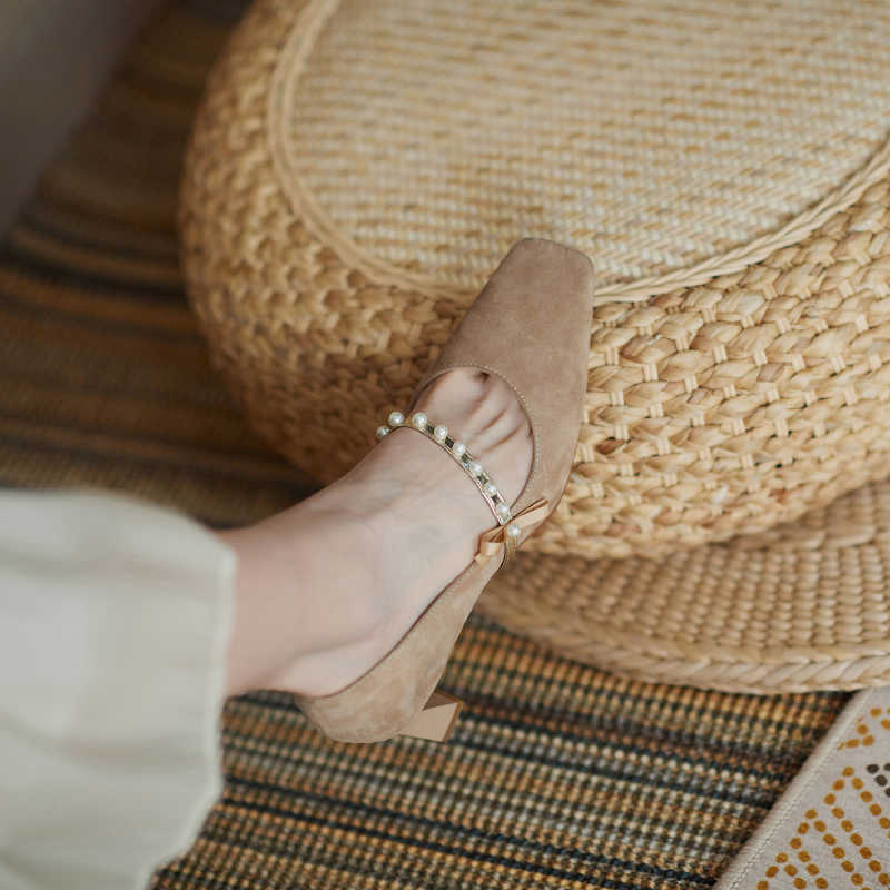 Brown sandal on a foot with a woven ottoman in the background