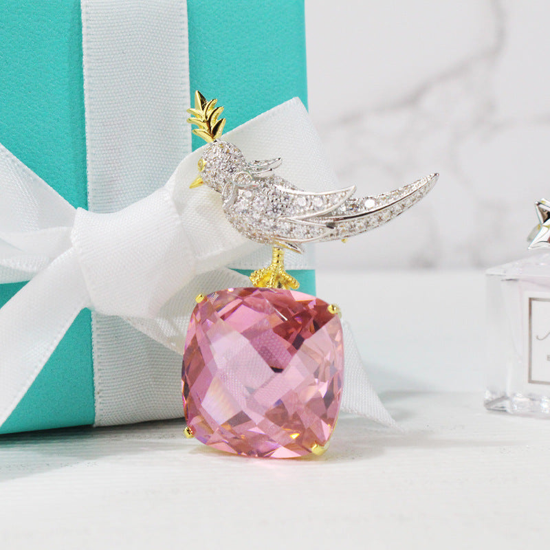 Jewelry with pink gemstone and bird design in front of a Tiffany & Co. box.