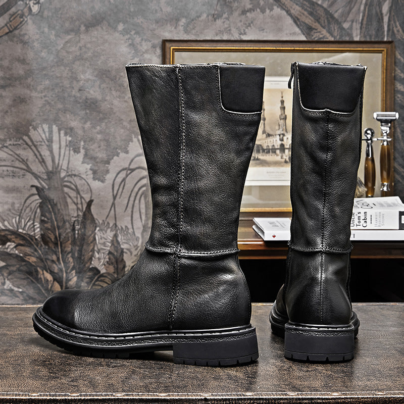 Pair of black leather boots on a textured surface with a decorative background