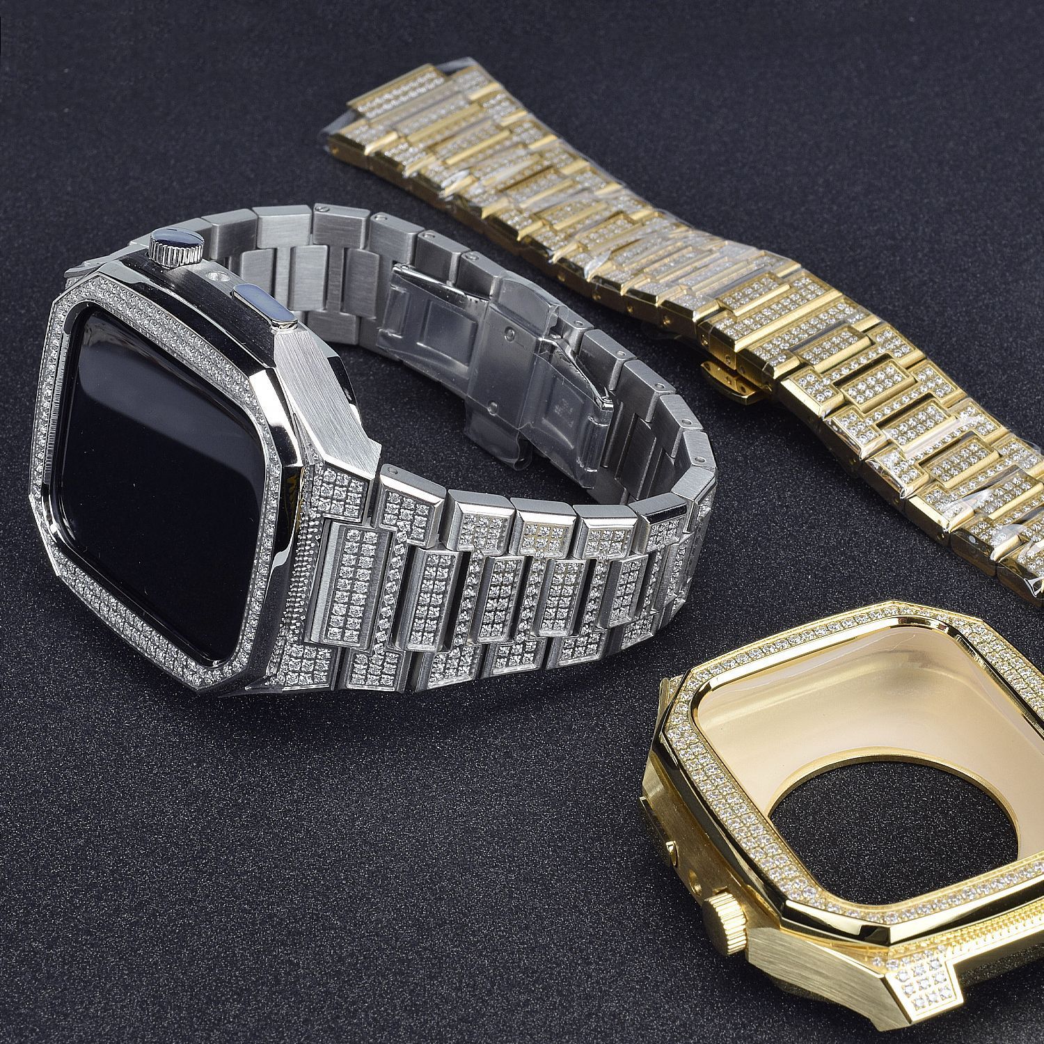 Two diamond-encrusted watch bands, one silver and one gold, on a dark background.