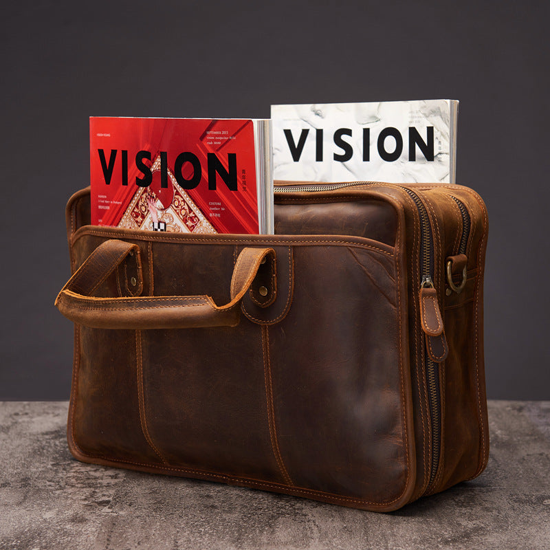 Brown leather bag with 'VISION' books on a dark background