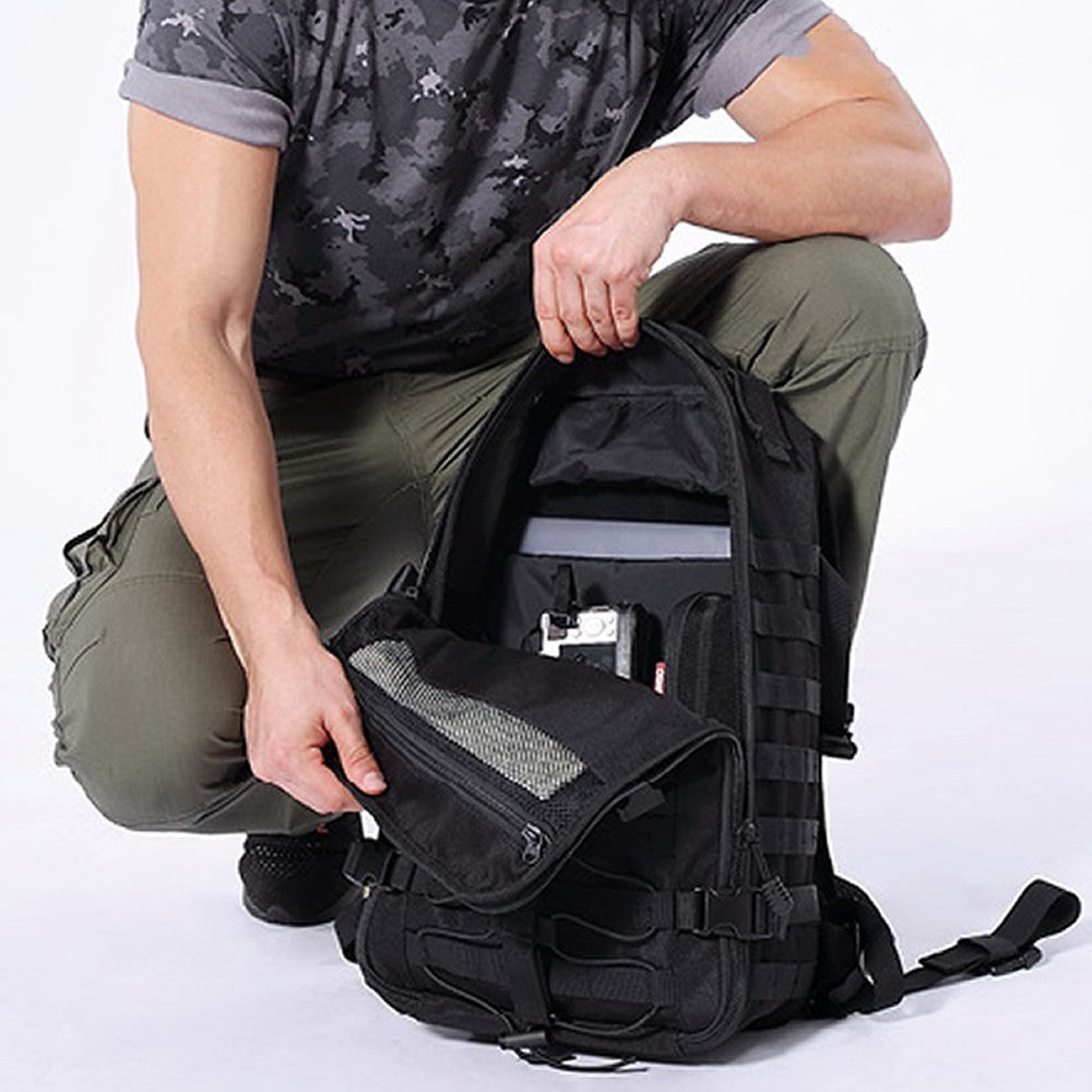 Person kneeling with a black tactical backpack on a white background