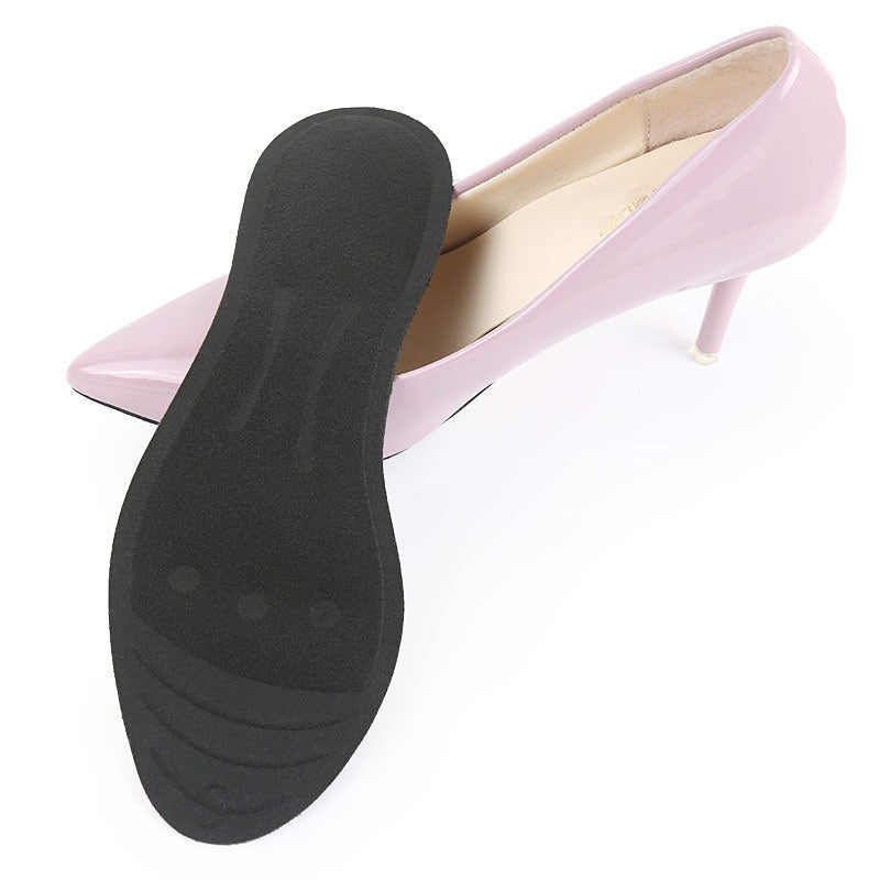 Black shoe sole with pink high-heeled shoe on a white background