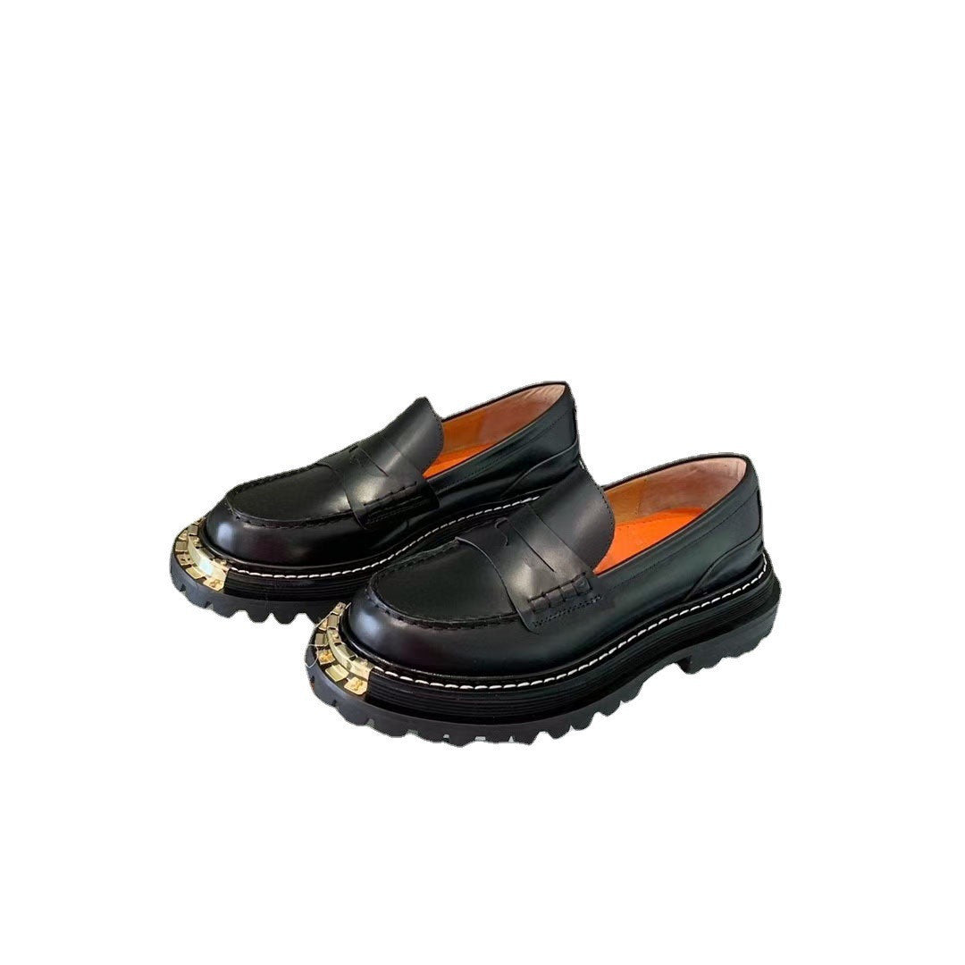 Pair of black loafers with gold accents on a white background