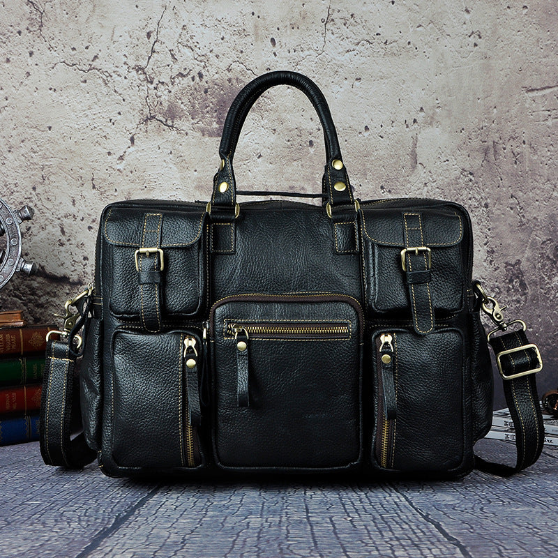Black leather bag with multiple pockets and straps on a textured surface