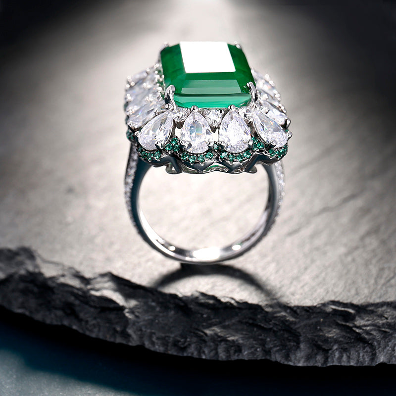 Elegant ring with emerald and diamonds on a textured surface
