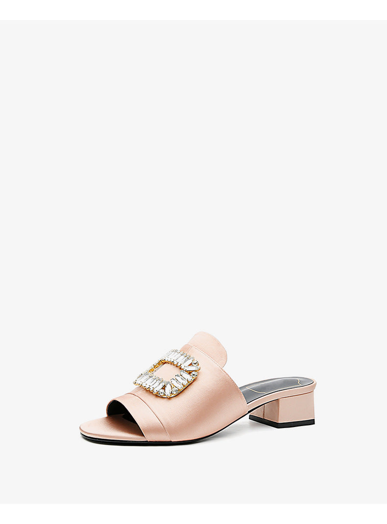 Pink sandal with a decorative buckle on a white background