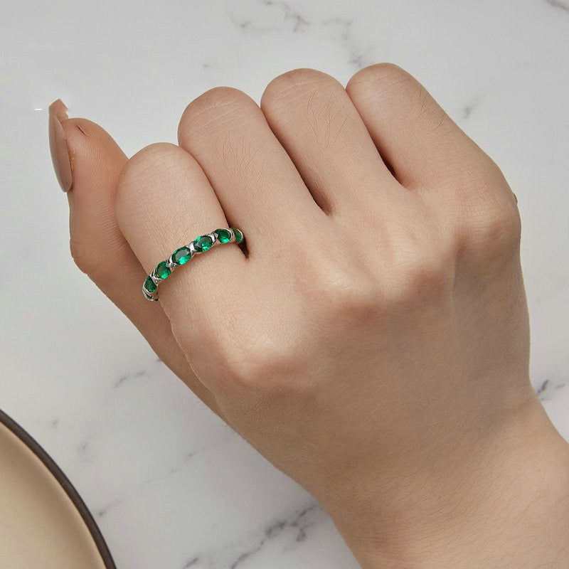 Hand wearing a green gemstone ring on a marble surface