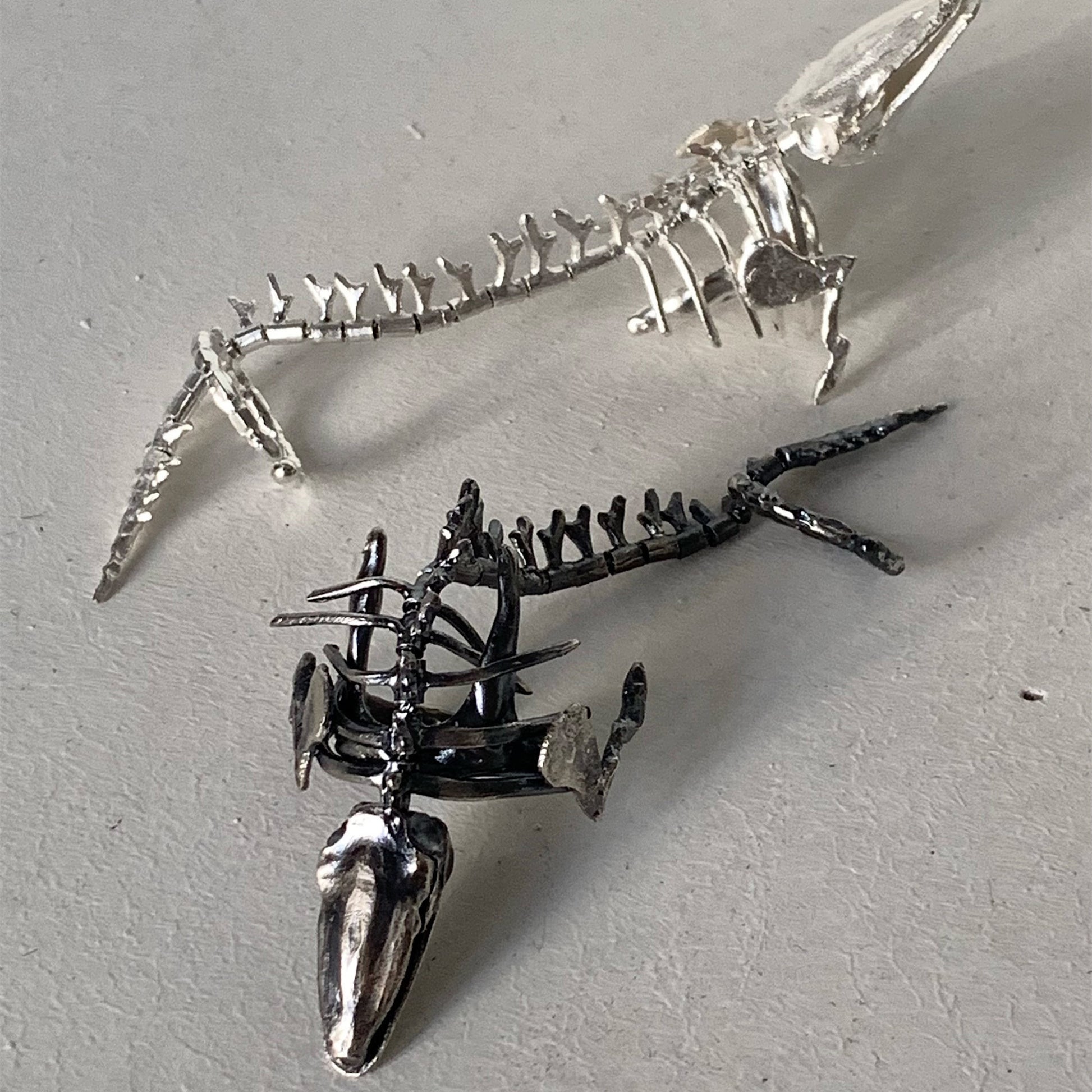 Metallic dinosaur skeleton models on a gray surface