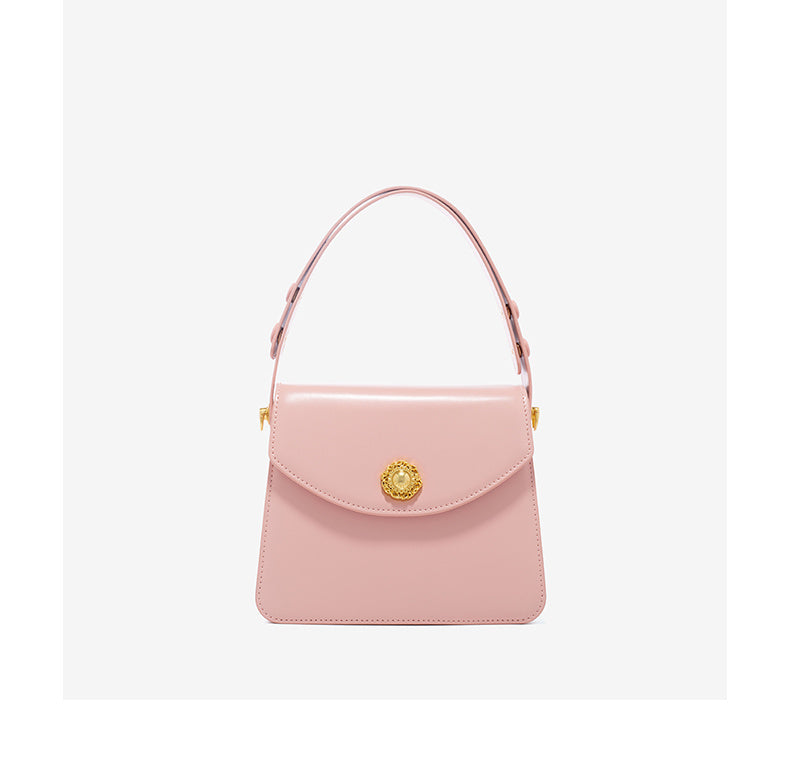 Pink handbag with a gold clasp on a light gray background