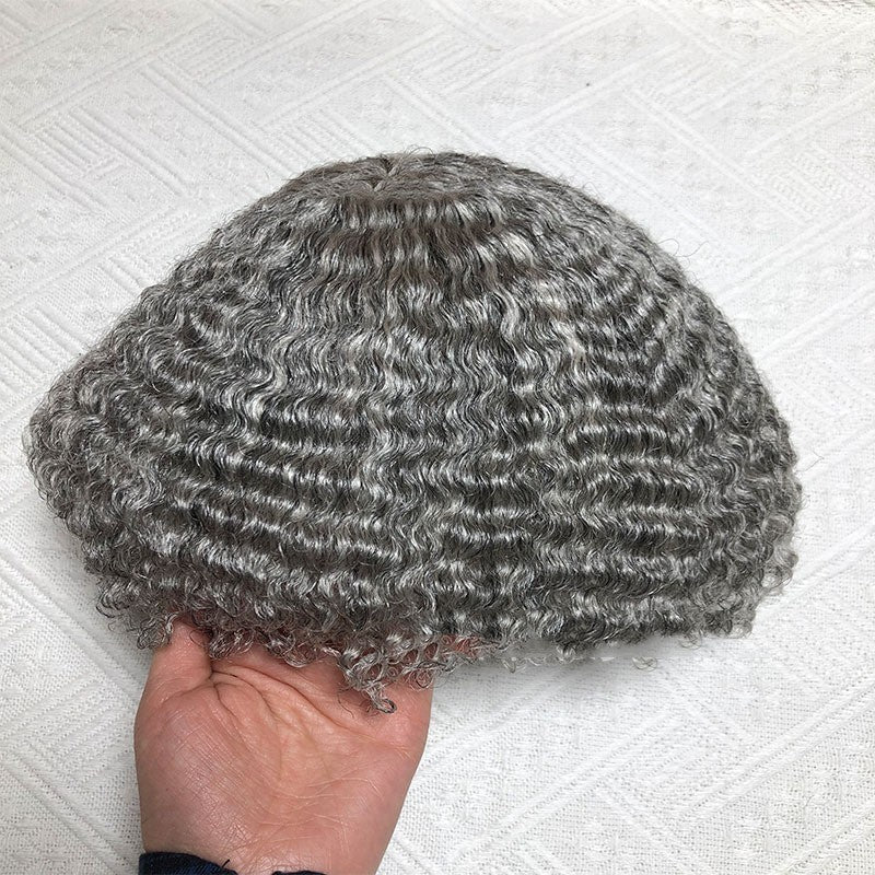 Gray curly wig held by a hand on a textured white background