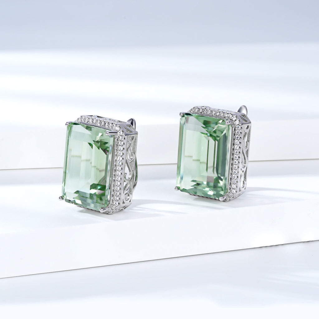 Pair of green gemstone earrings with silver frames on a white background