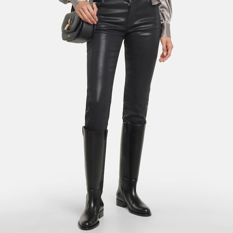 Person wearing black leather leggings and knee-high boots on a white background