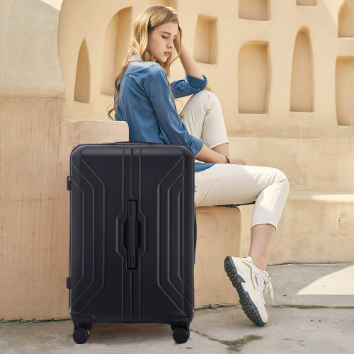 Woman sitting next to a black suitcase in an outdoor setting