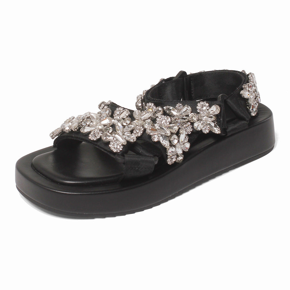 Black sandal with floral embellishments on a white background