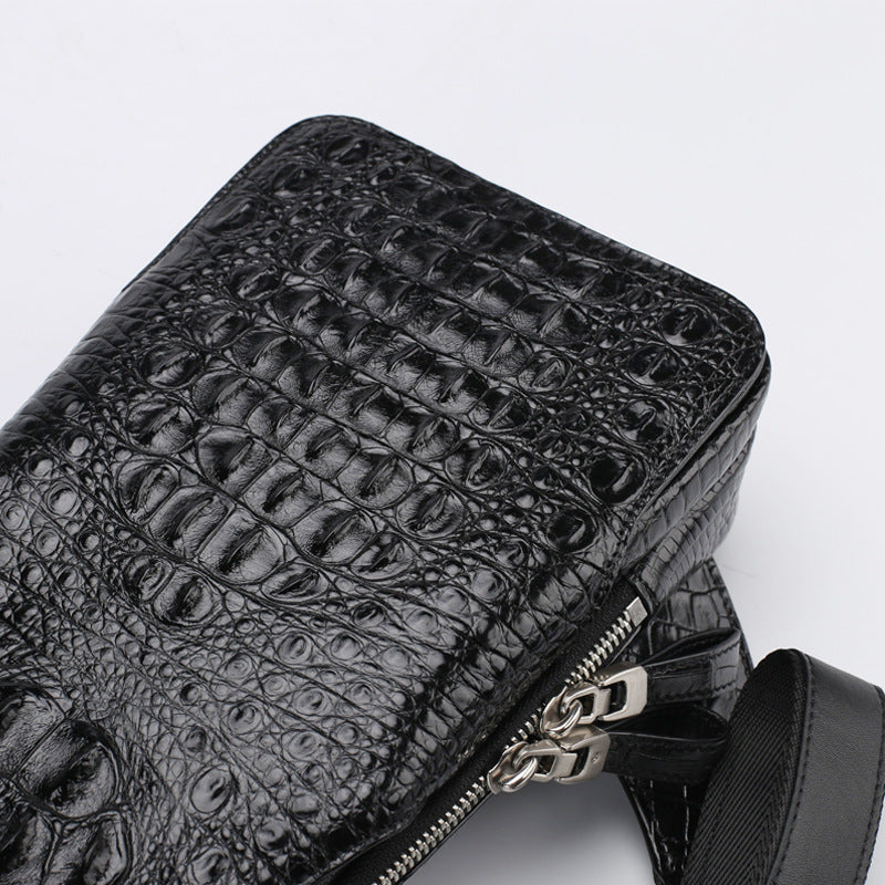 Black crocodile-patterned handbag with a silver zipper on a light gray background