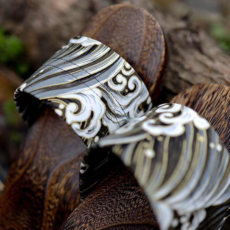 Two silver rings with intricate designs on a wooden surface