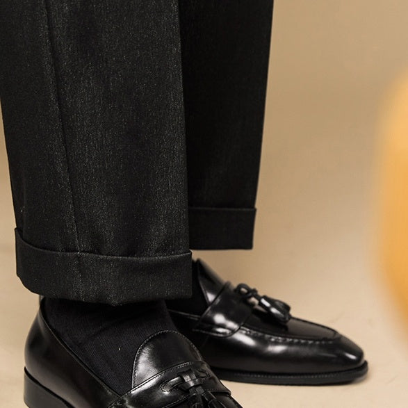 Black dress shoes and pants on a beige background