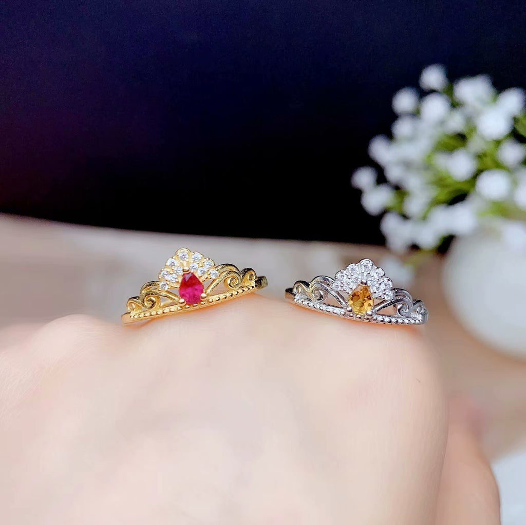 Two tiara-shaped rings with gemstones on a blurred background