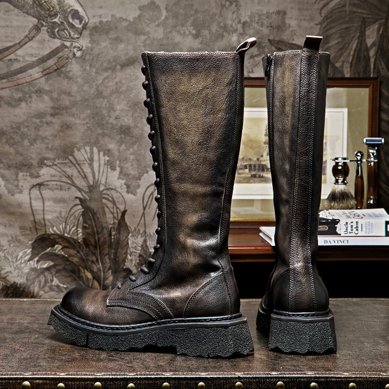 Pair of brown leather knee-high boots on a wooden surface with a decorative background.