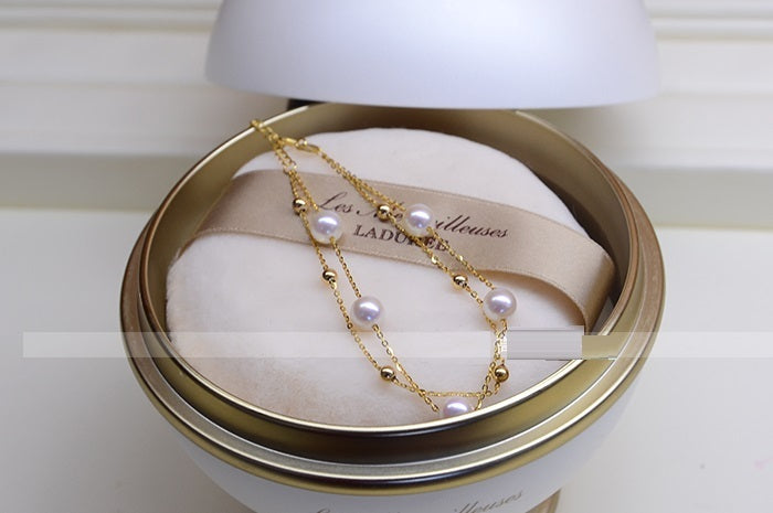 Gold and pearl necklace in a jewelry box with 'LADURÓE' branding.