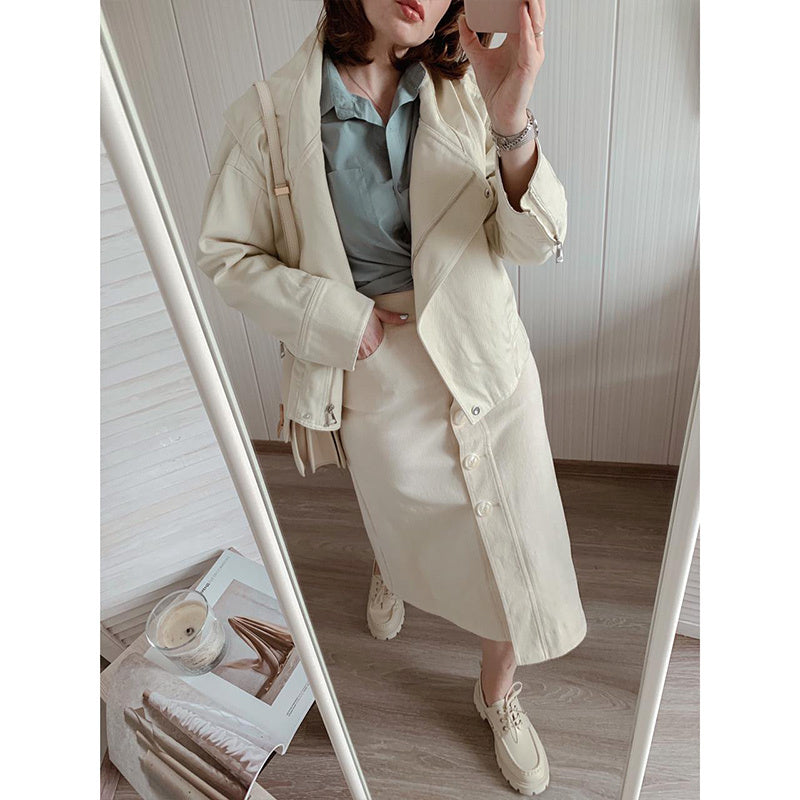 Person wearing a beige trench coat standing in front of a mirror.