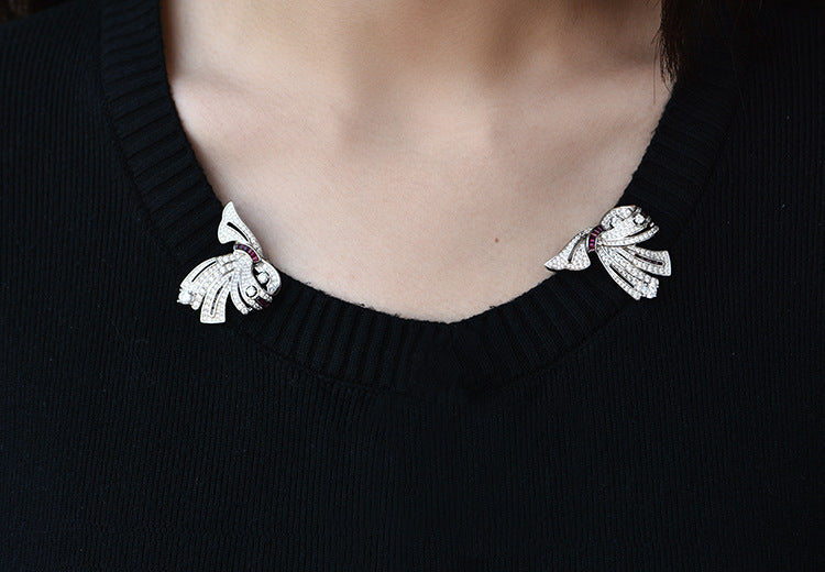 Close-up of a person wearing a black sweater with decorative bows on a plain background