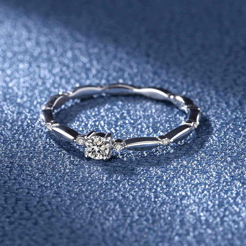 Silver ring with a diamond on a textured blue surface